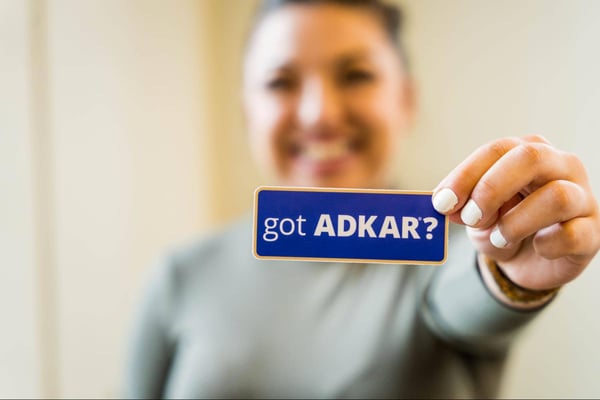 A woman holding a card that says, "Got ADKAR?"