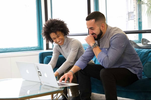 a man and a woman looking at a laptop